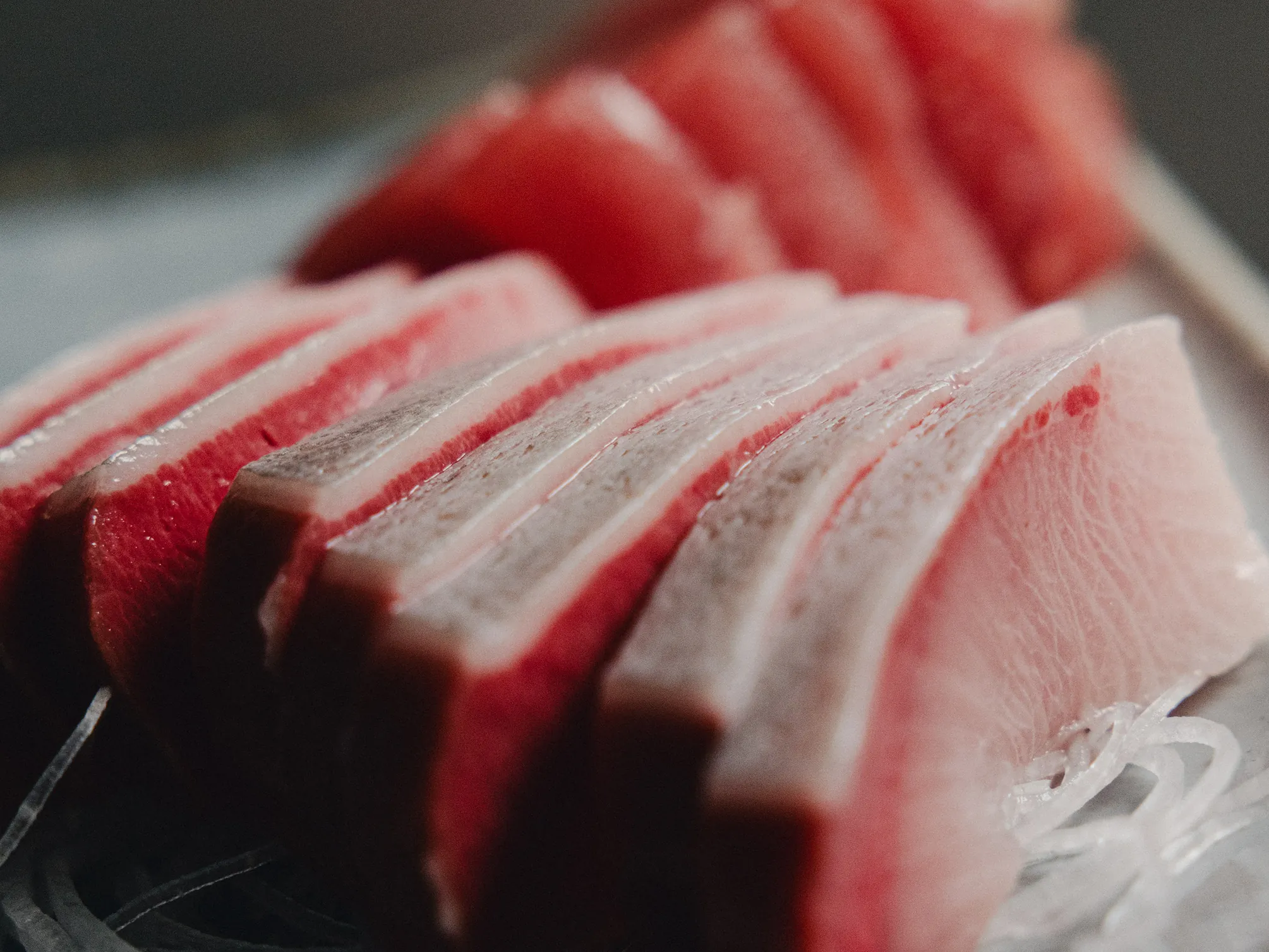 Slices of hamachi fanned across a white plate
